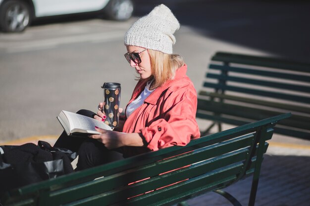Женщина, сидя на скамейке с книгой