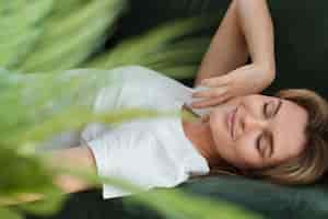 Free photo woman resting on the couch and blurred plant