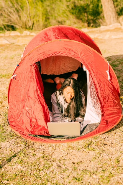 무료 사진 텐트에서 쉬고 노트북을 사용하는 여자