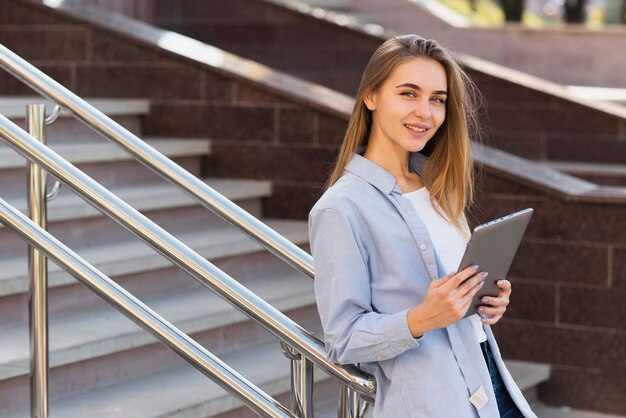 手すりで休んで、タブレットを保持している女性