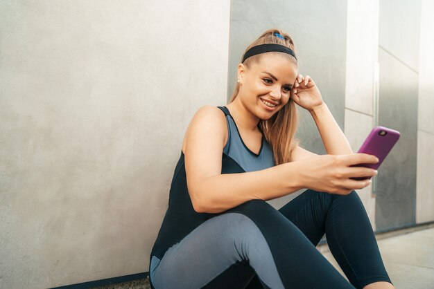 スマートフォンでスポーツウェアで休んでいる女性