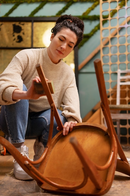 Free photo woman restoring wooden chair  full shot