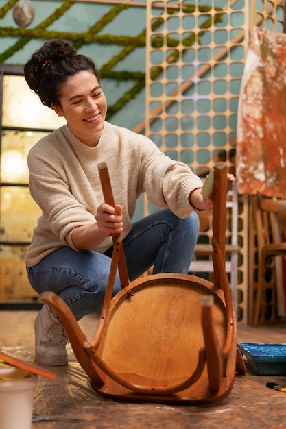 Free photo woman restoring wooden chair  full shot