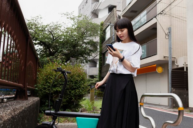 Woman riding bicycle in the city and looking at smartphone