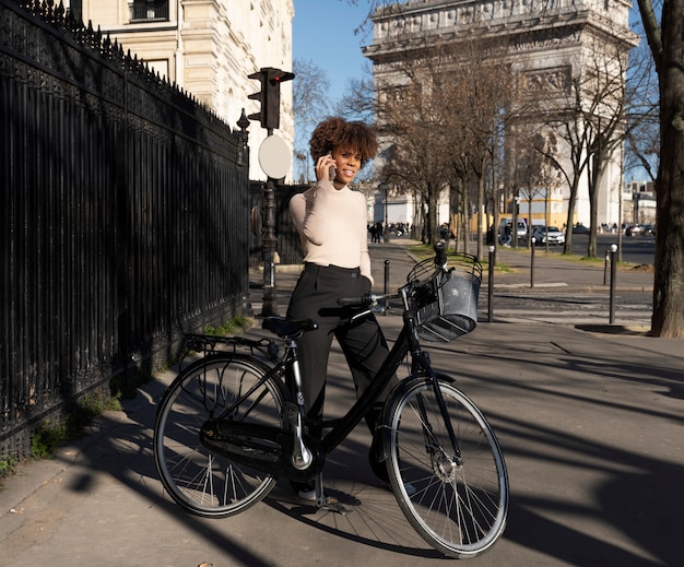 Женщина едет на велосипеде и разговаривает по смартфону в городе во франции
