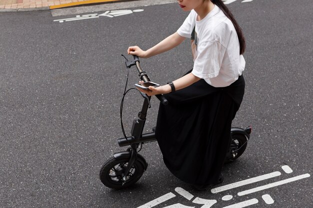 市内で電動自転車に乗ってスマートフォンを持っている女性