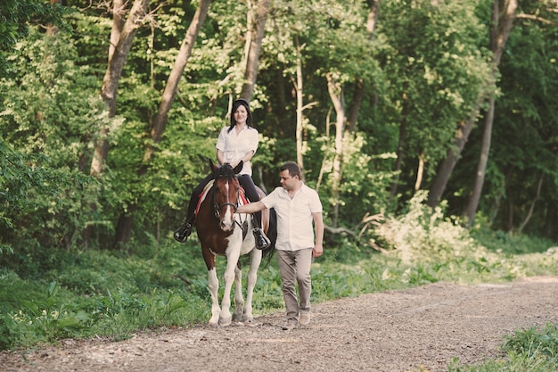 Woman riding a horse and her husband walk