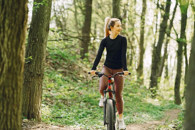 숲에서 산악 자전거를 타는 여자