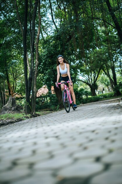 Woman riding a road bike in the park. Portrait of young beautiful woman on pink bike.