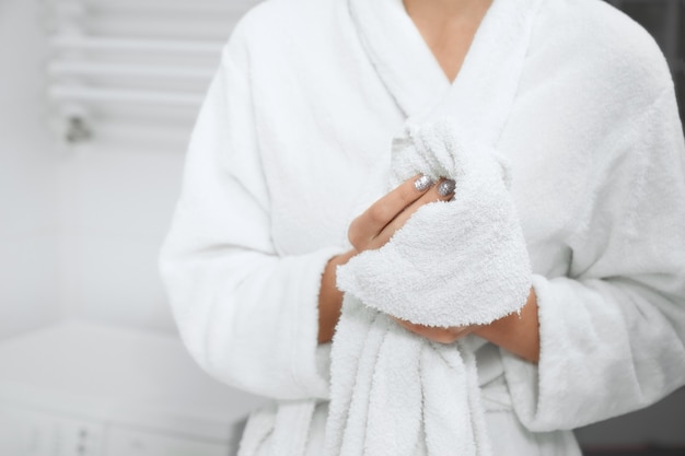 Woman in robe standing in bathroom with white towel