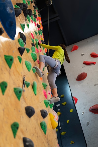 アリーナで屋内でロック クライミングをする女性