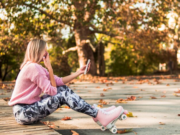 Woman in roller skates laughing at smartphone