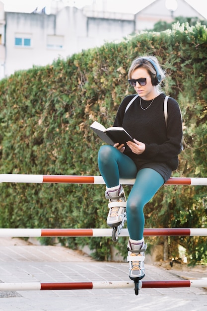 Woman in roller skates reading on fence