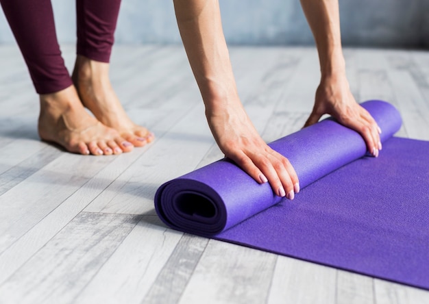 Женщина катит ее коврик для йоги
