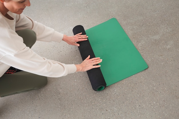 Free photo woman rolling yoga mat
