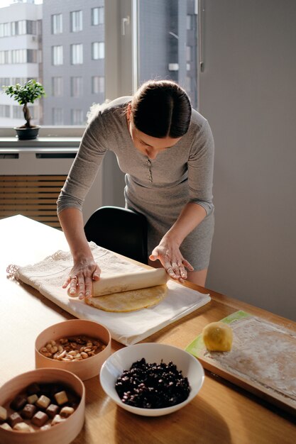 Woman rolls out the dough with a rolling pin in the sun rays