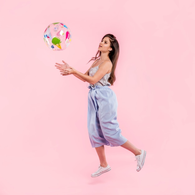 Foto gratuita donna in pagliaccetto che gioca con il beach ball