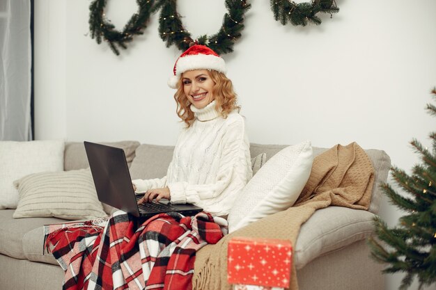 Woman in a room. Blonde in a white sweater. Lady with laptop.