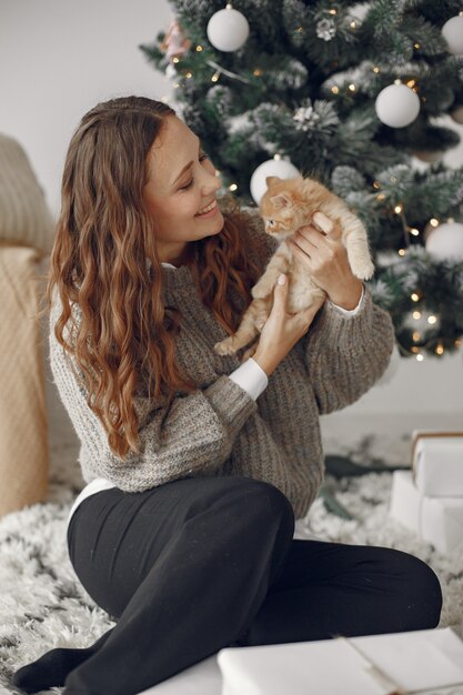 Woman in a room. Person in a gray sweater. Lady with little kitty.