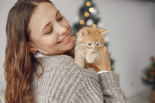 部屋の女性。灰色のセーターを着た人。小さな子猫を持つ女性。