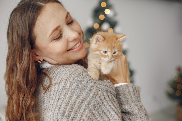 Woman in a room. Person in a gray sweater. Lady with little kitty.