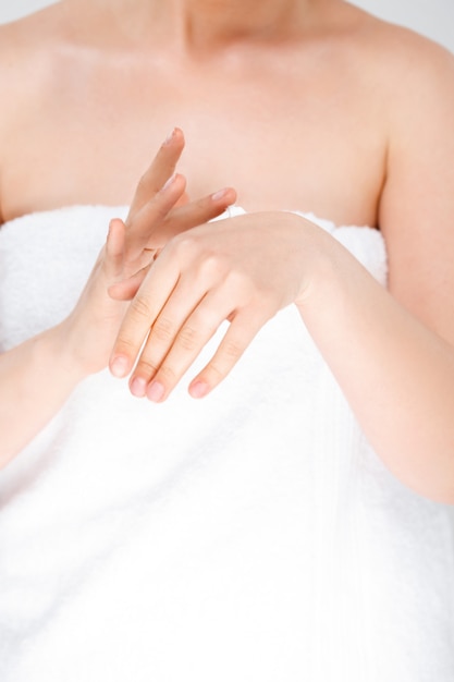 Woman rubbing cream on hands, wear towel