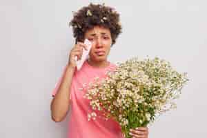 Foto gratuita la donna strofina gli occhi rossi acquosi con il tessuto tiene il bouquet di fiori di camomilla essendo allergica al polline isolato su bianco