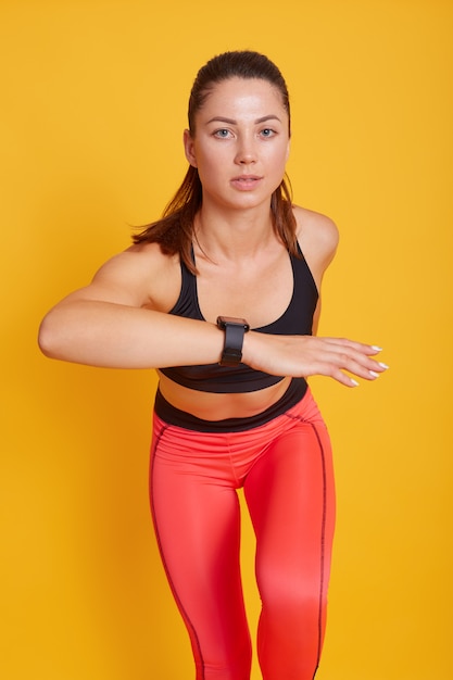 Woman runner posing isolated over yellow, dynamic movement, fit lady working out in gym, wearing bra and leggings