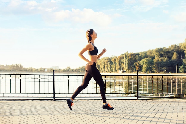 Woman running by the lake at sunset