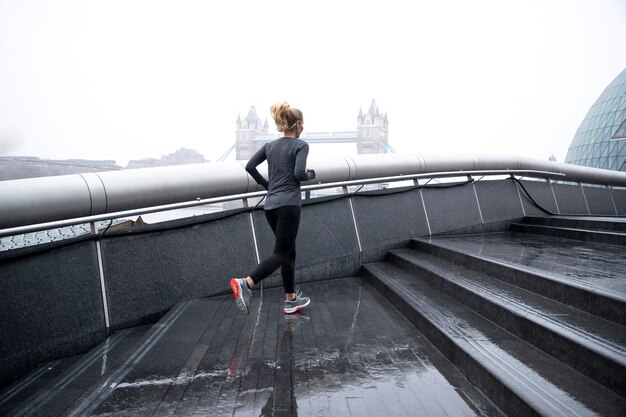 Woman running in the city streets while it rains