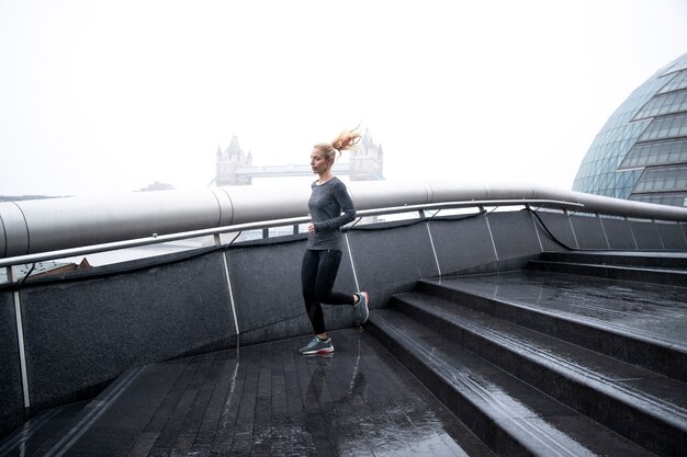 Woman running in the city streets while it rains