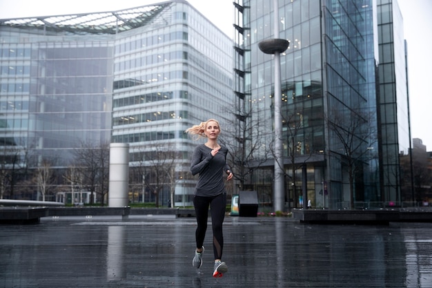 Foto gratuita donna che corre e fa i suoi esercizi fuori mentre piove