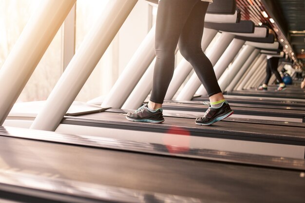 Woman running in a gym on a treadmill concept for exercising, fitness and healthy lifestyle