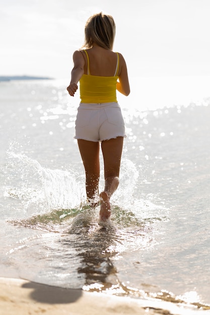 무료 사진 해변에서 물을 통해 실행하는 여자