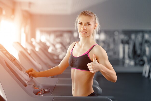 Woman running on a treadmill with a raised thumb