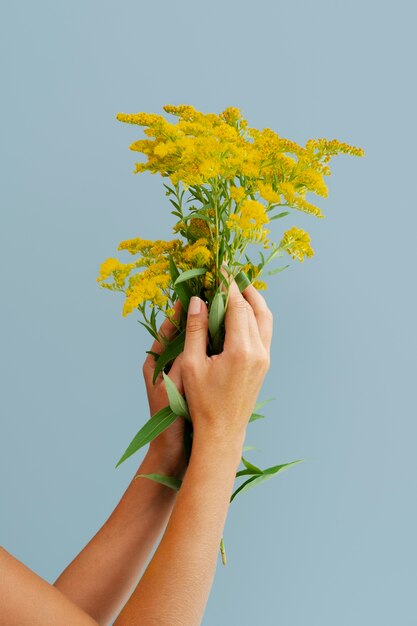노란 꽃을 들고 있는 여성의 팔