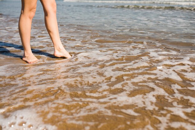 Босые ноги женщины в мелководной морской воде на пляже