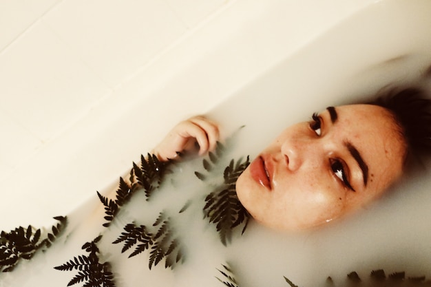 Free photo woman's body submerged in water holding green plant