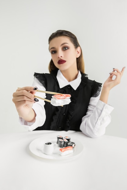 プラスチック製の女性が食べる寿司、エココンセプト。有機的な世界を失う。