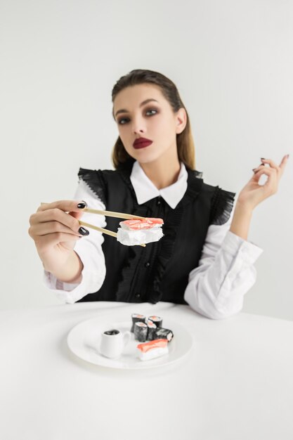 Woman's eating sushi made of plastic, eco concept. Loosing organic world.