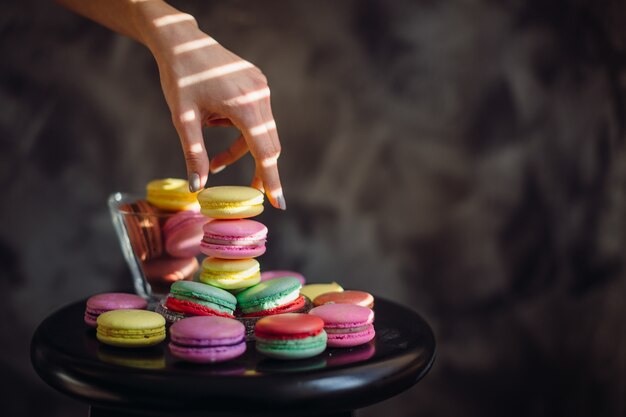 Woman's elegant hand takes yellow macaroon 