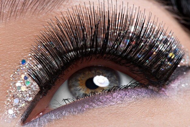 woman's eye with long black false eyelashes and creative fashion bright makeup