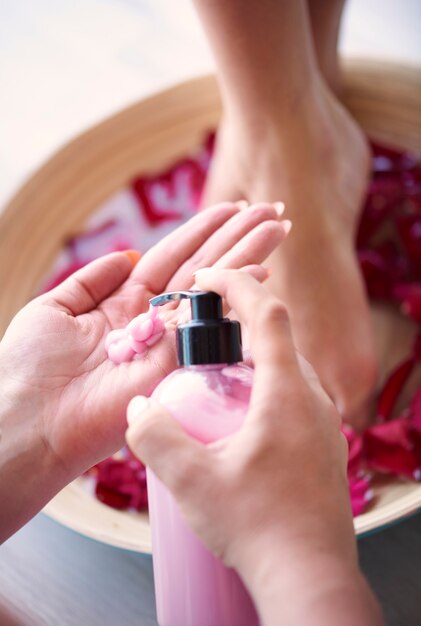 Woman's feet in bowl with water and petal