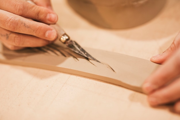 Woman's hand carving on the wet rectangular shape with tools