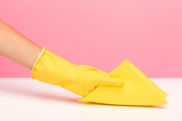 The woman's hand cleaning on a pink wall. Cleaning or housekeeping concept