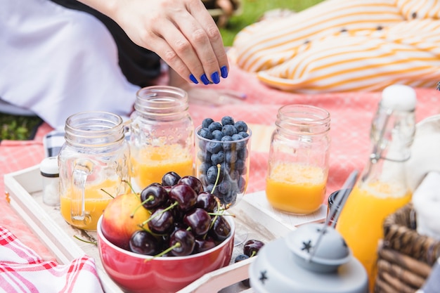 マンゴージュースの瓶と果物とブルーベリーを食べる女性の手