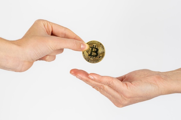 Free photo woman's hand giving a bitcoin coin to another woman