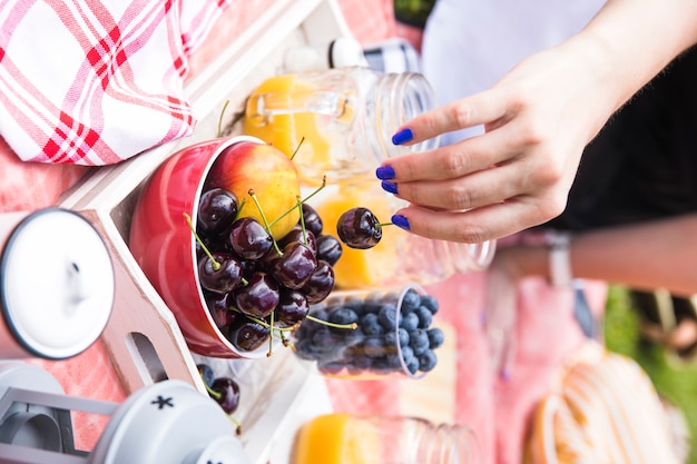 Woman's hand holding cherry from the bowl