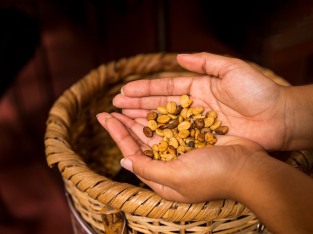 Foto gratuita chicchi di caffè della holding della mano della donna sopra il cestino di vimini