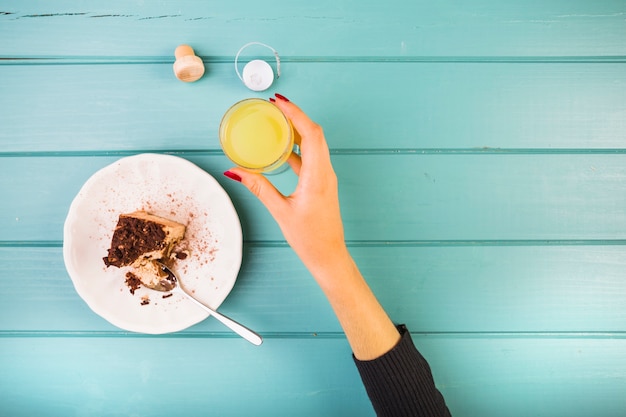 Woman's hand holding drink with pastry on table